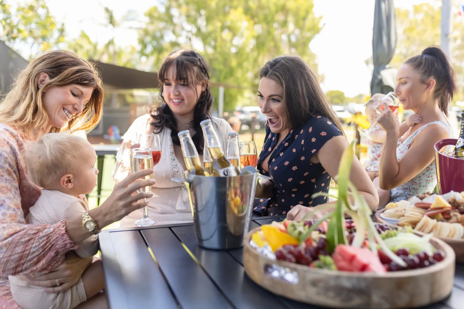 Members and families sharing drinks and a grazing platter in the beer garden at golden hour