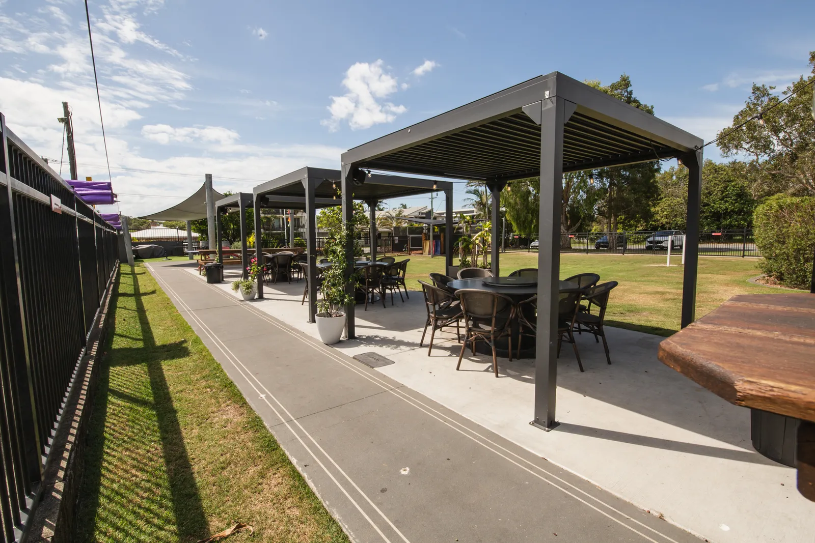 The pergolas — covered outdoor dining under louvred roofs beside the lawn